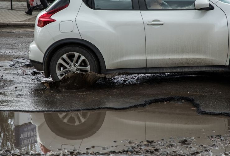 Car passing through large pothole