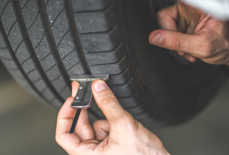 Man checking car tyre tread