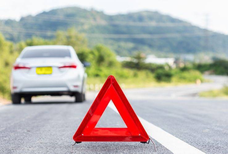 Broken down car at side of road with warning triangle