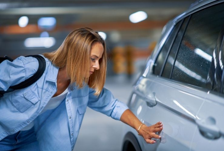 Lady inspecting scratch on car in car park