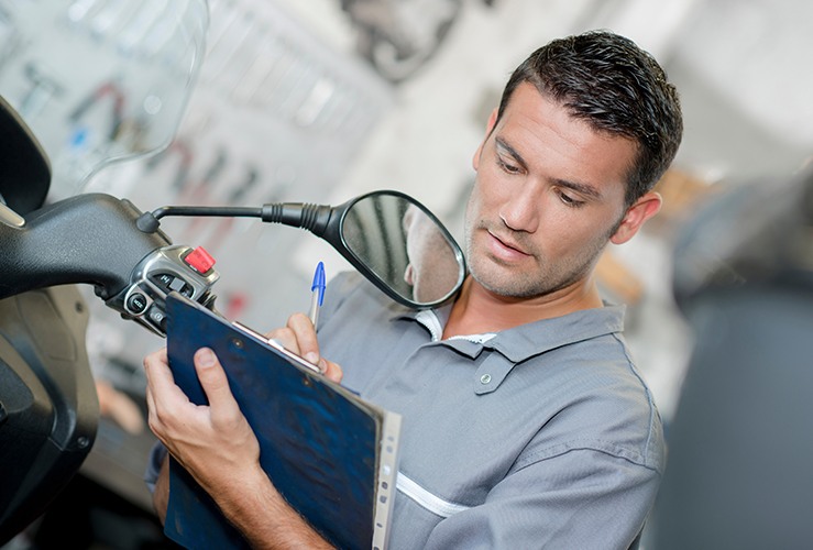 Man carrying out an MOT check on a motorbike