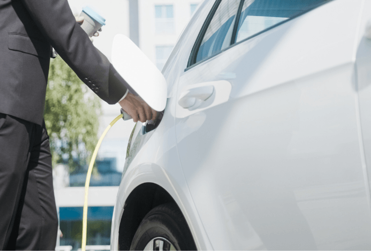 Man charging EV, with coffee in hand